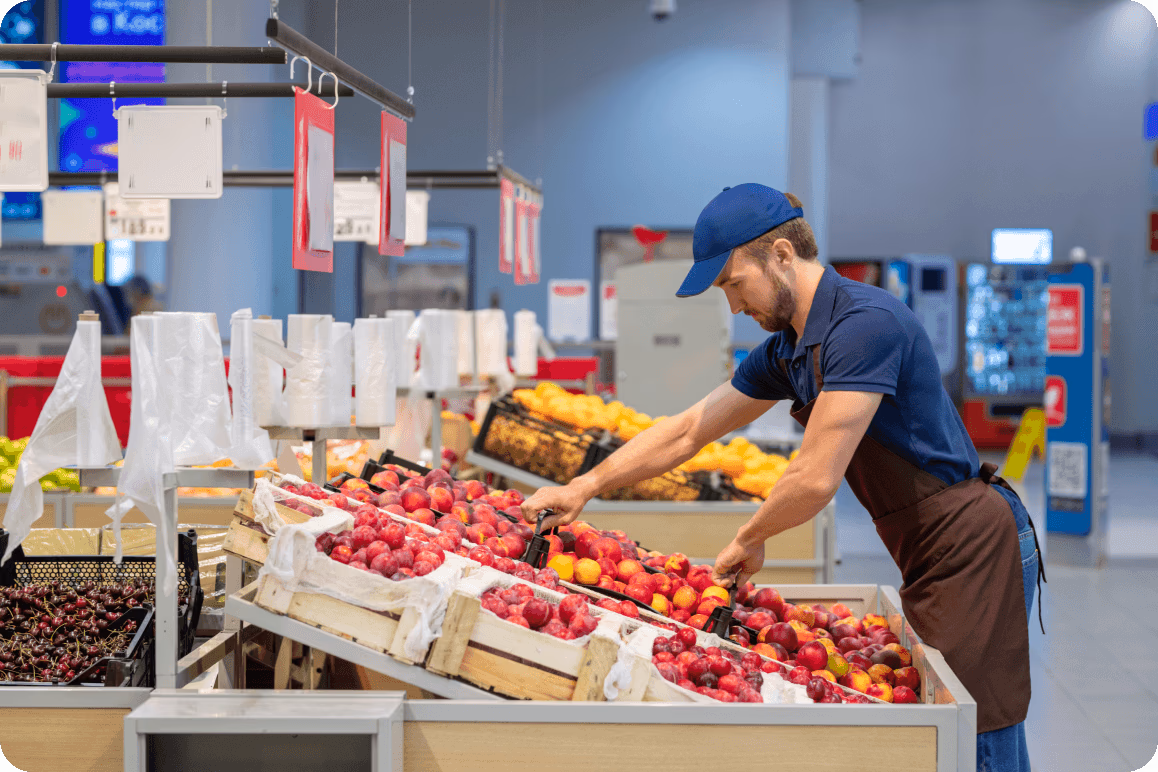 Personale che rifornisce frutta in un negozio al dettaglio