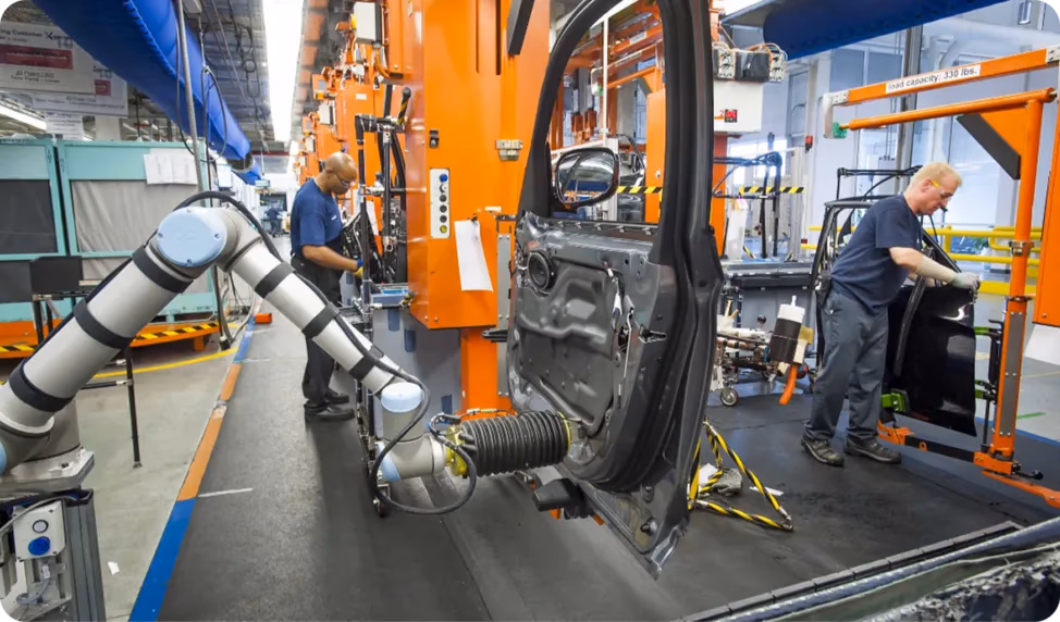 Robôs trabalhando ao lado de funcionários em uma fábrica de automóveis