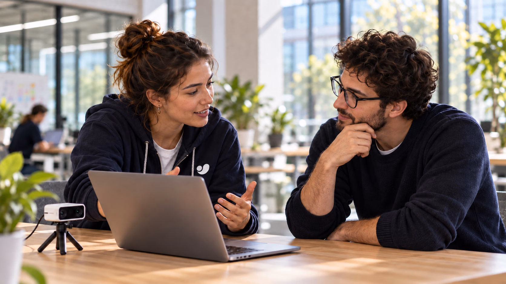 Two Ultralytics creators discussing a project beside a laptop and camera